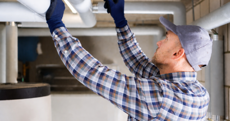 Plumber inspecting basement pipes for spring plumbing problems in Northeast Ohio